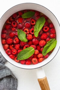 A pan filled with raspberries and mint leaves.