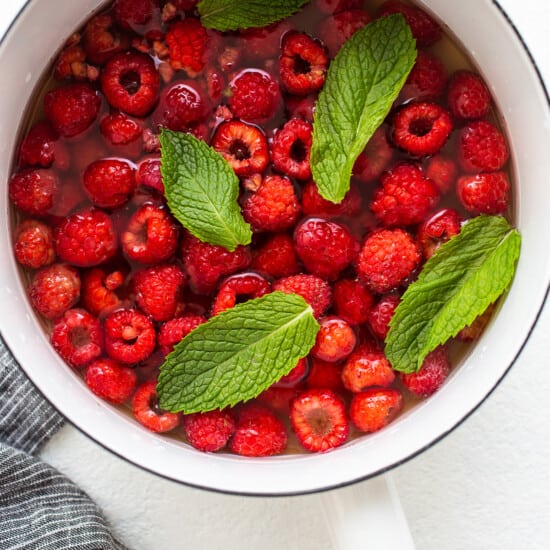 A pan filled with raspberries and mint leaves.