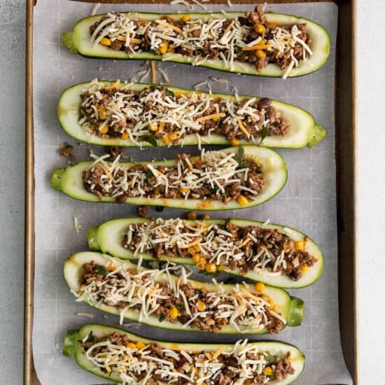 Zucchini boats with meat and cheese on a baking sheet.