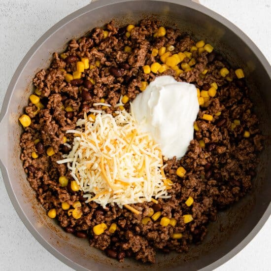 A skillet filled with beef, corn and sour cream.