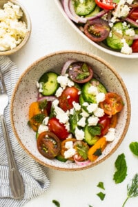 Cucumber tomato salad topped with feta cheese in a bowl.