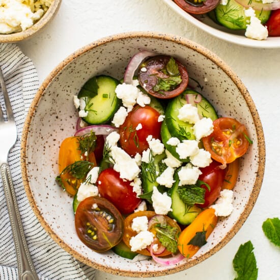 Cucumber tomato salad topped with feta cheese in a bowl.
