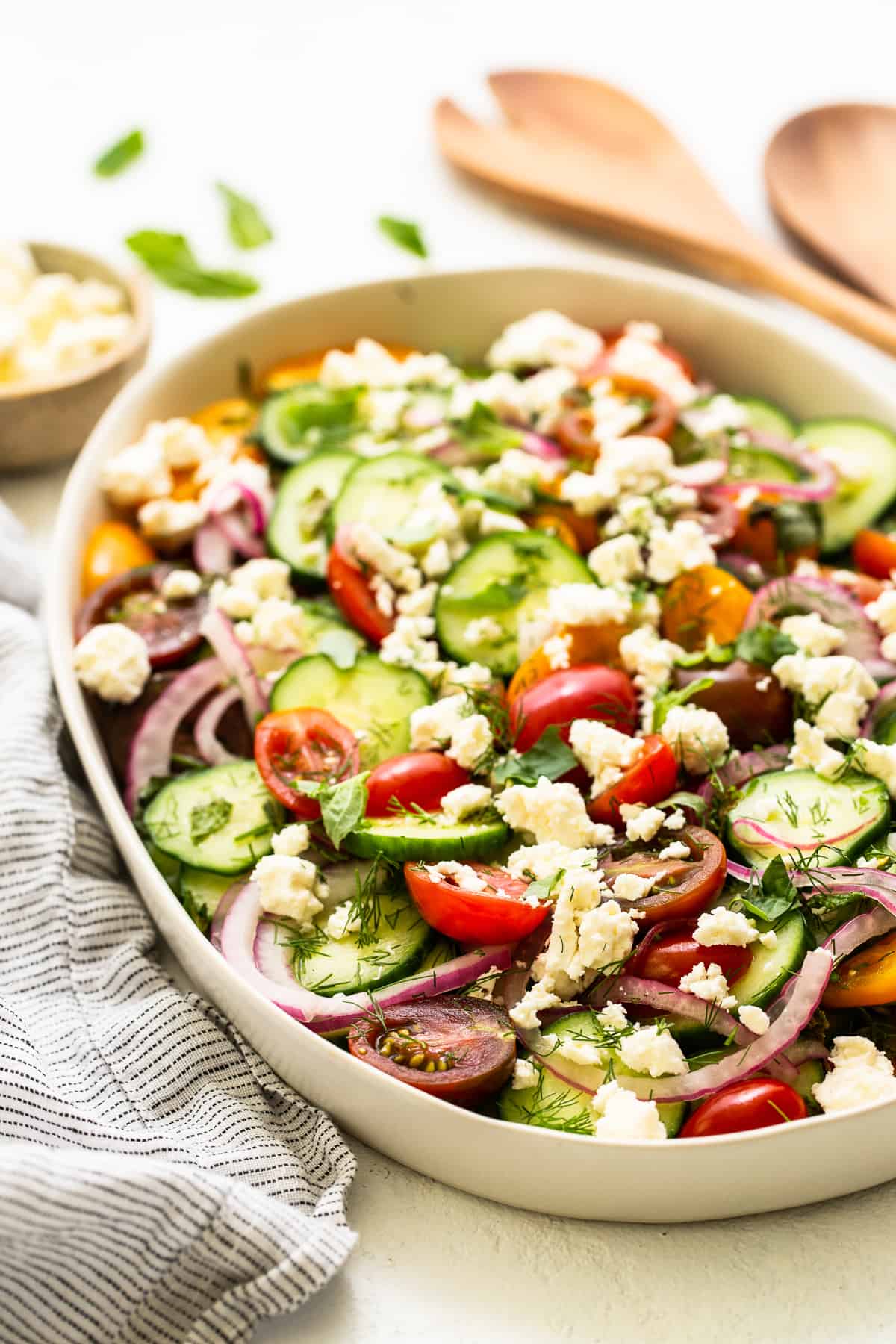 Cucumber tomato salad in a bowl topped with feta. 