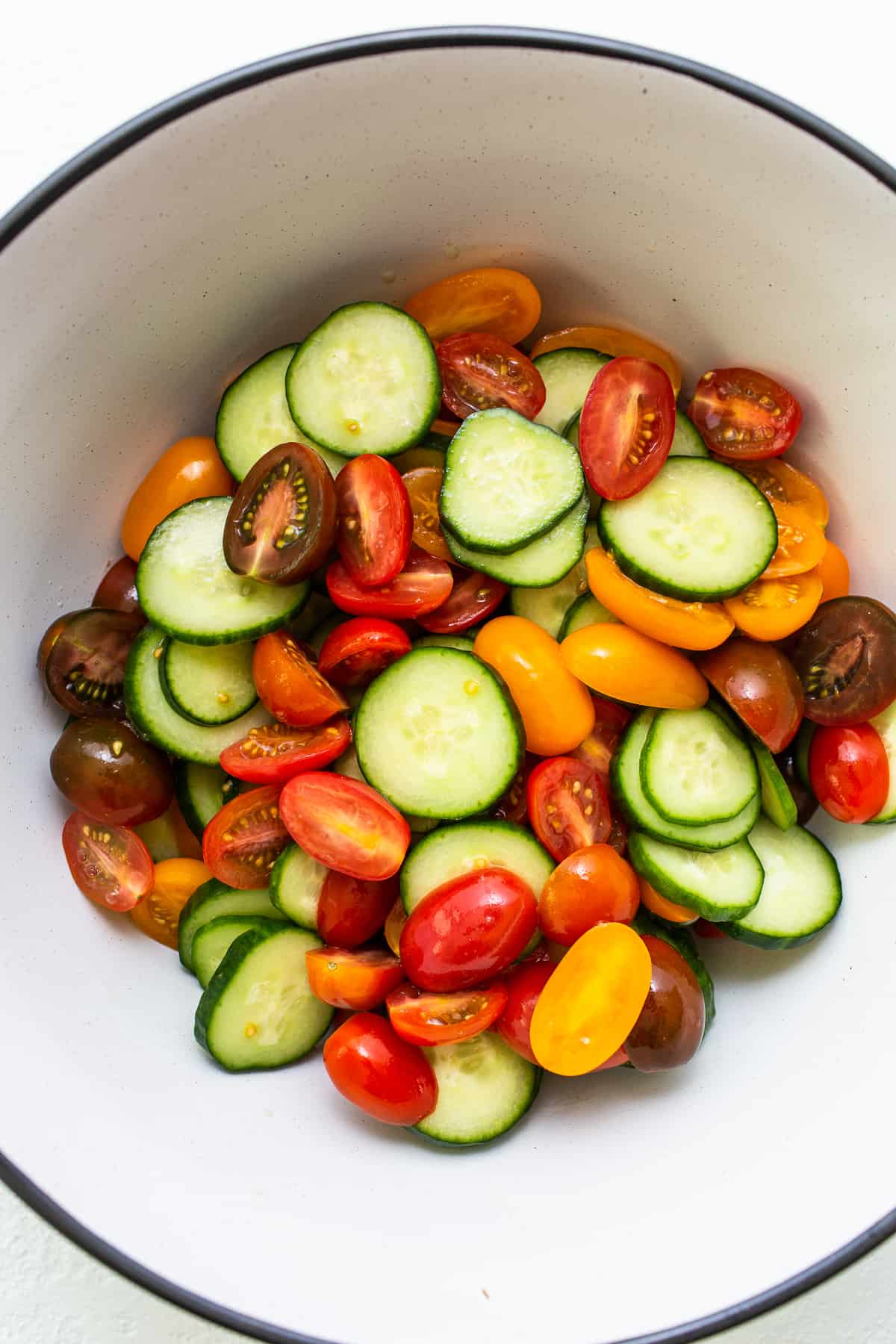 Tomatoes and cucumbers in a mixing bowl. 