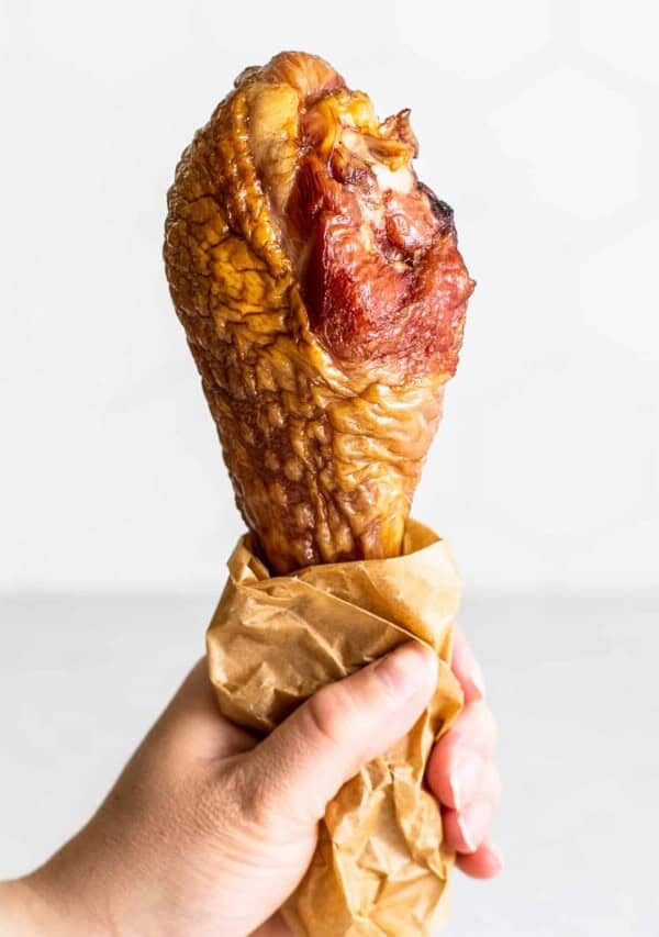 a hand holding up a smoked turkey leg