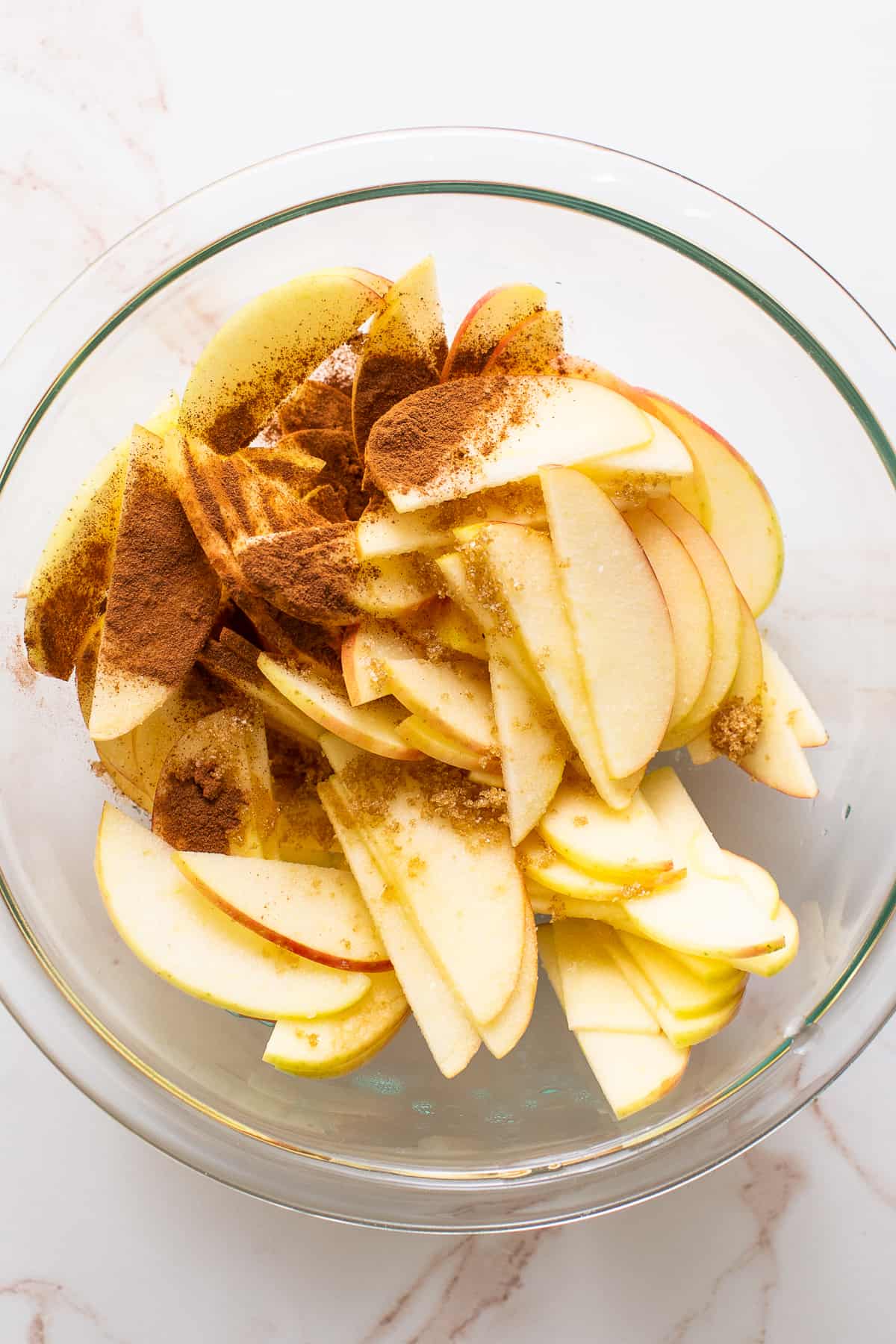 A bowl of sliced apples with cinnamon on top.