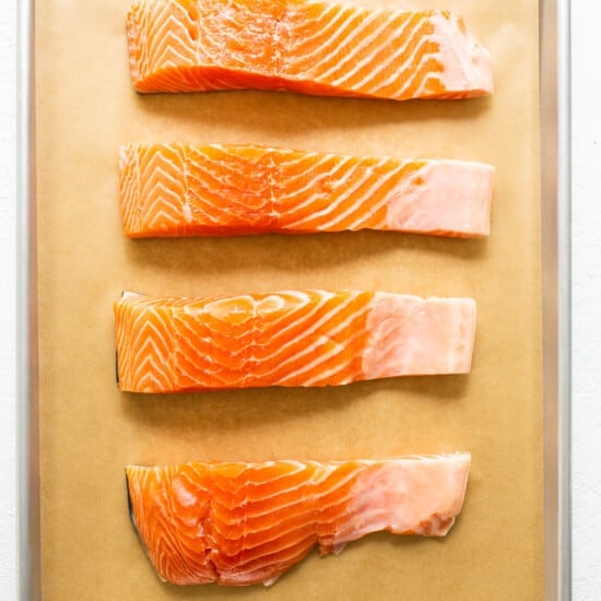 Raw salmon on a lined baking sheet.