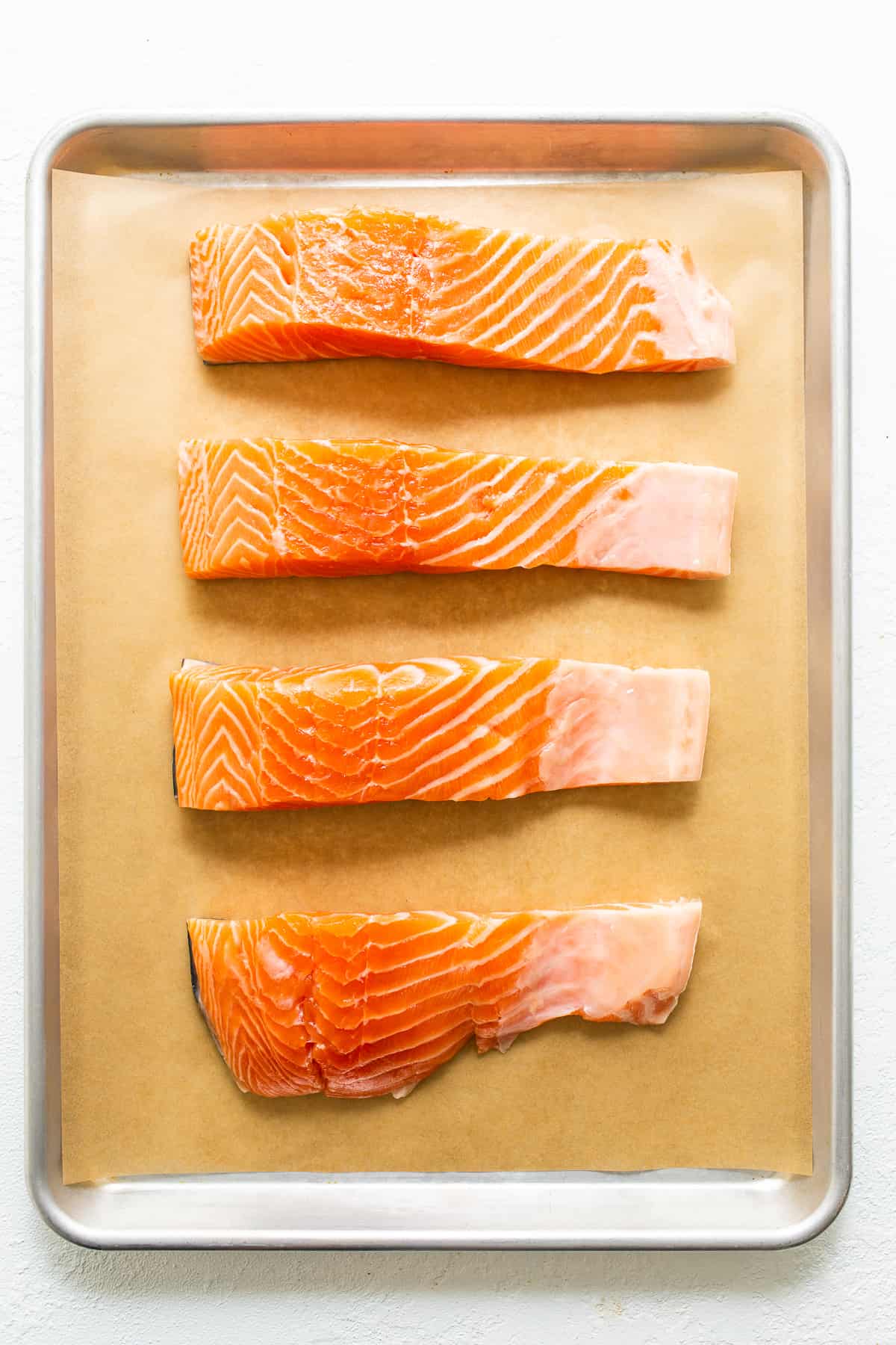 Raw salmon filets on a baking sheet. 