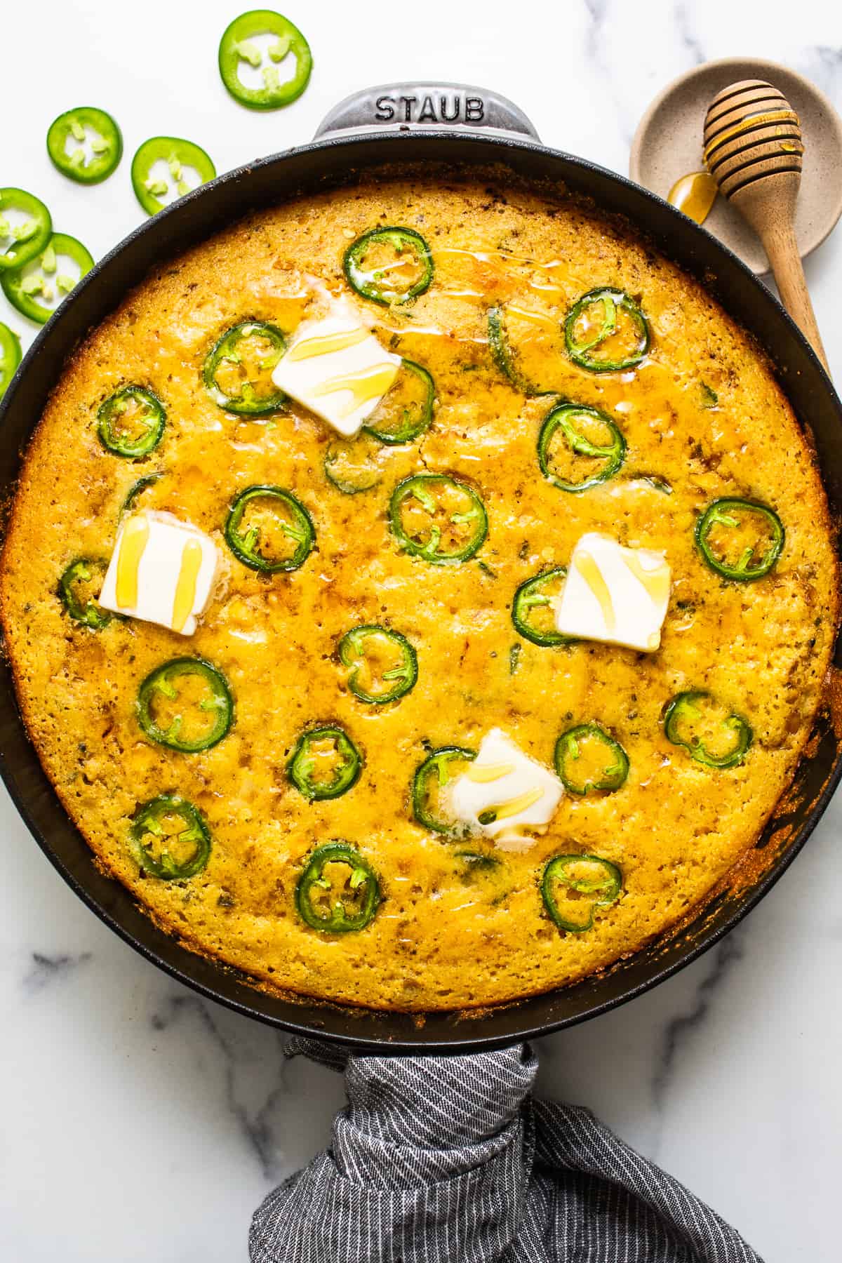 Jalapeno corn pudding in a cast iron skillet topped with pads of butter.