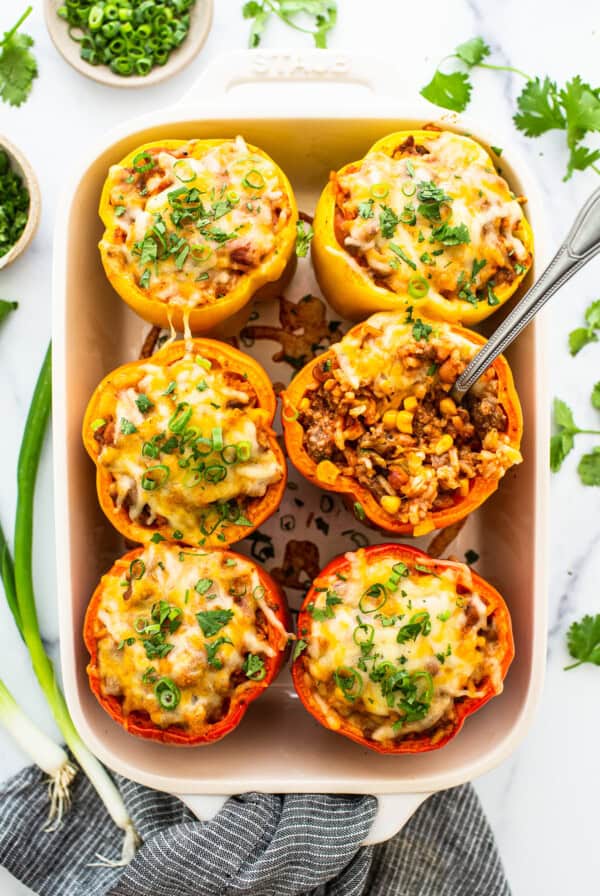 Stuffed peppers in a casserole dish and topped with cheese.
