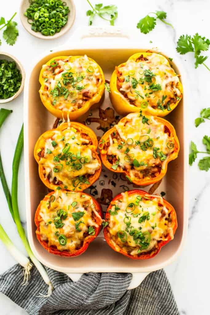Stuffed peppers in a casserole dish topped with green onion.