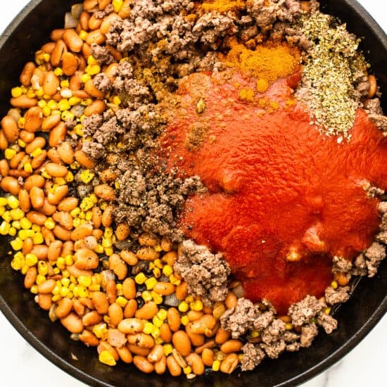 A skillet filled with ground beef, beans and tomatoes.