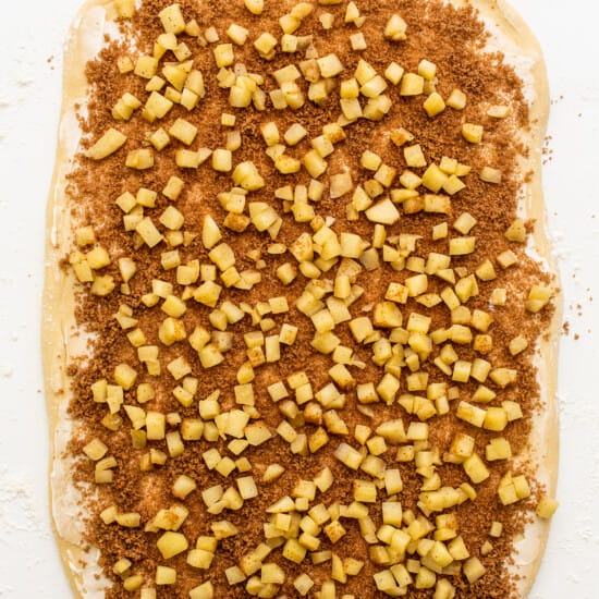 A pizza covered in cinnamon and sugar on a white surface.