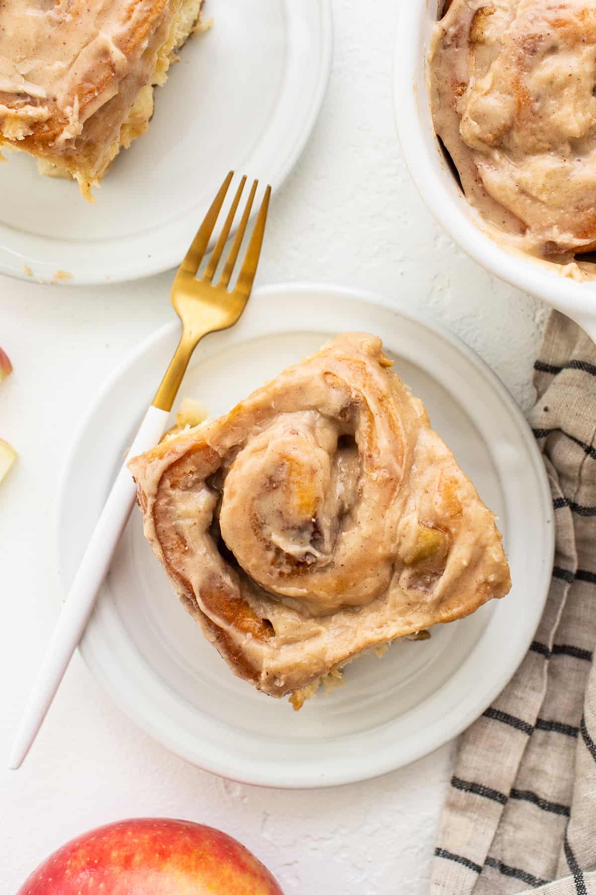 One apple cinnamon roll on a plate with a fork.