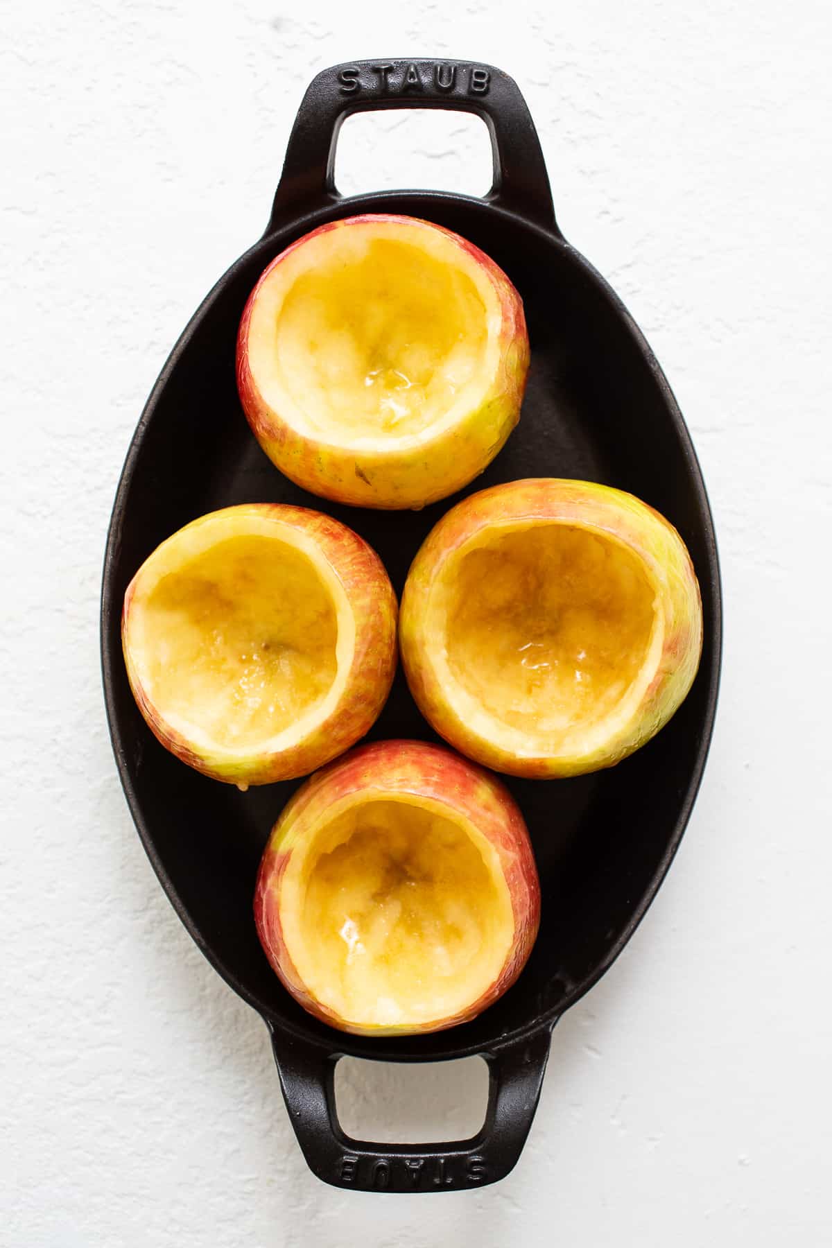 Cored apples in a baking dish.