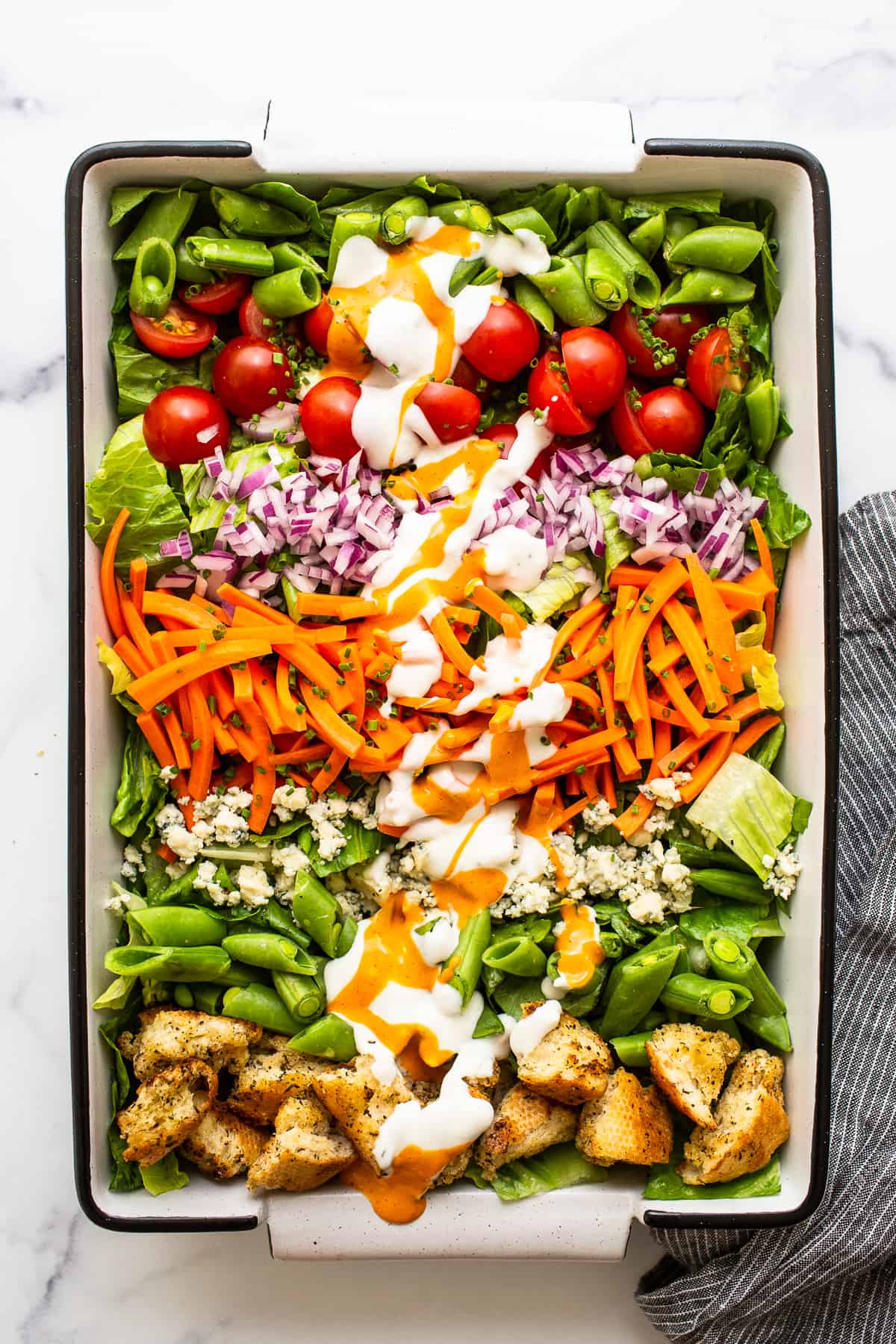 Garden salad in a serving dish topped with salad dressing.