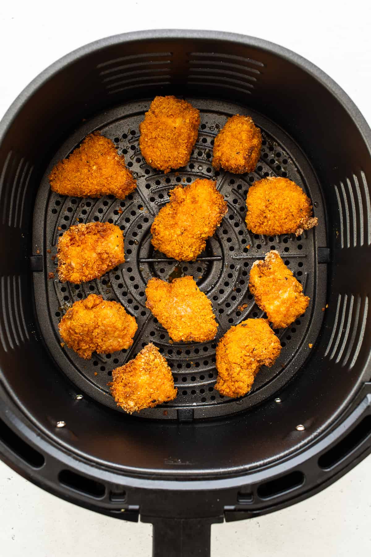 air frying chicken pieces in air fryer basket.