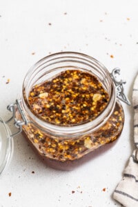 A jar of chili sauce with a spoon and a napkin.