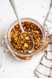 A spoonful of chile sauce in a glass jar.