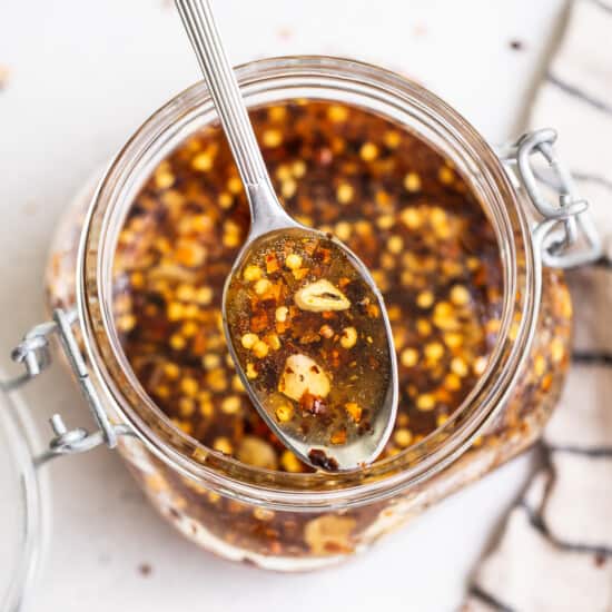 A spoonful of chile sauce in a glass jar.