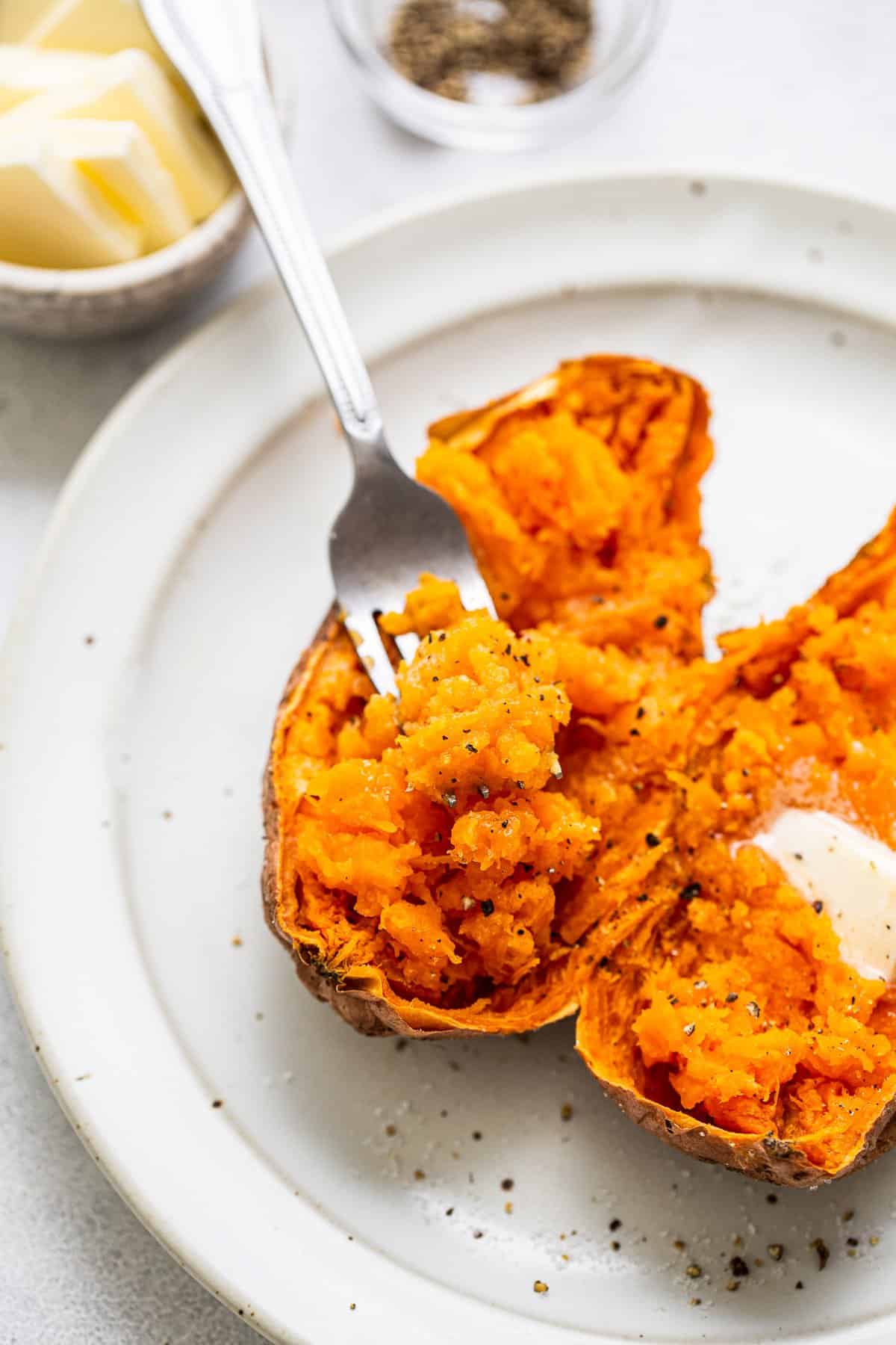 A fork scooping out the middle of a sweet potato. 
