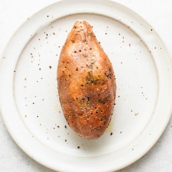 A sweet potato with holes on a plate.