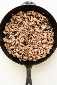 A frying pan with ground beef in it.