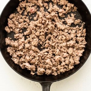 A frying pan with ground beef in it.