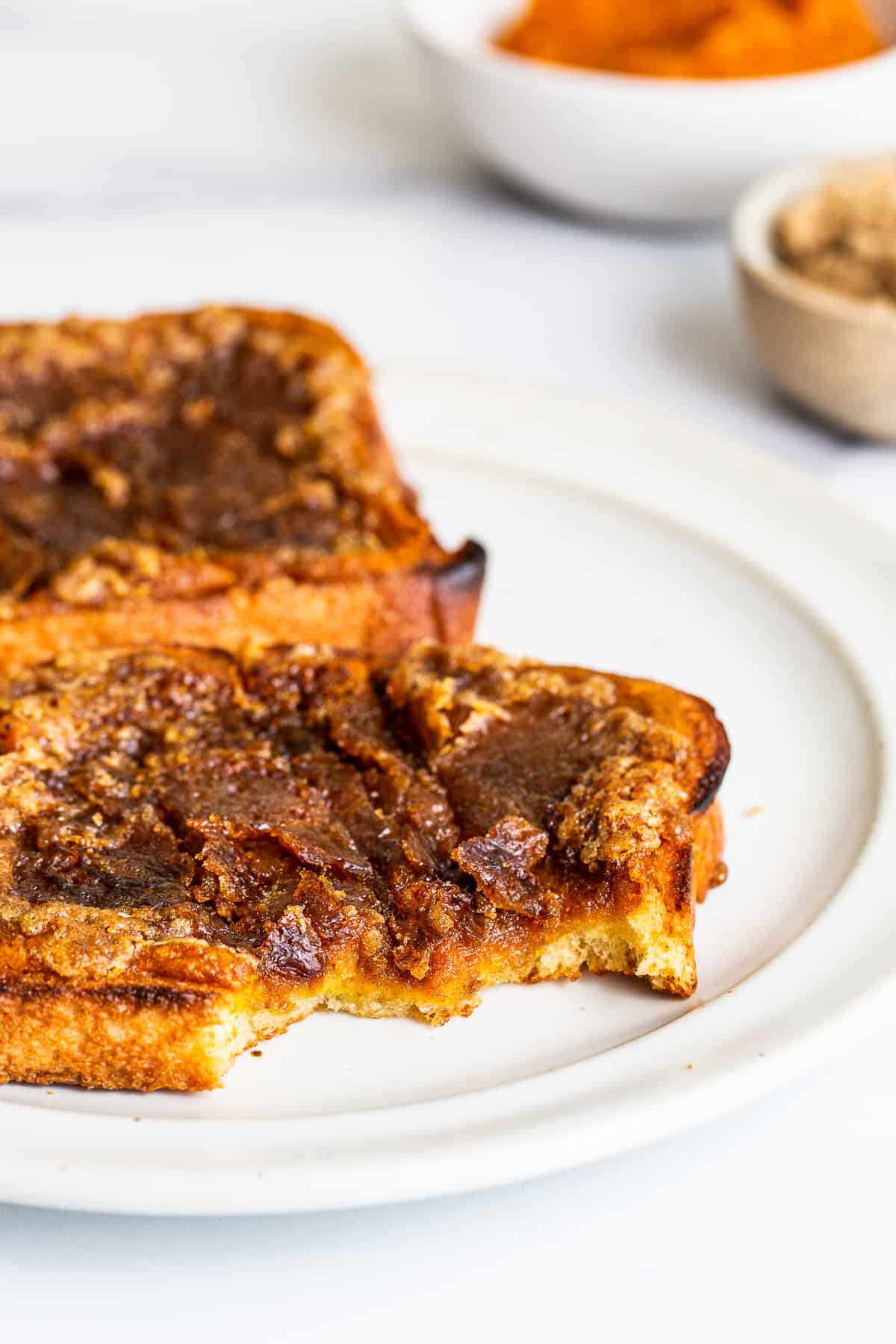 Pumpkin creme brulee french toast on a plate with a bite taken out of it.