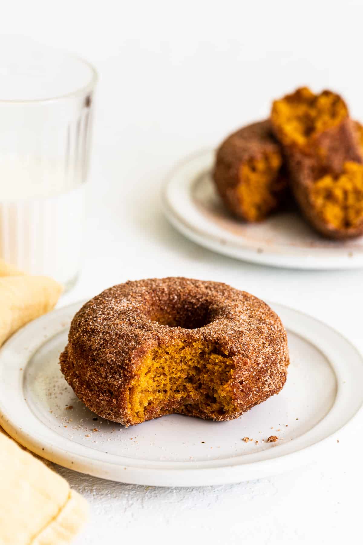 bite taken out of pumpkin donut on plate.