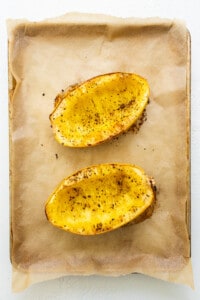 Two slices of baked sweet potato on a baking sheet.