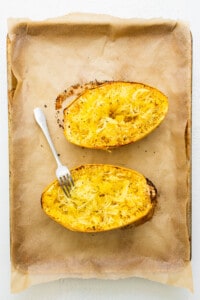 Two baked squash boats on a baking sheet with a fork.