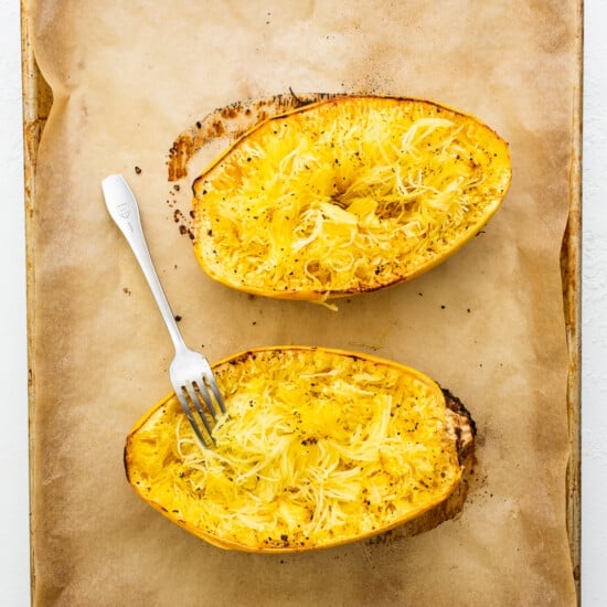 Two baked squash boats on a baking sheet with a fork.