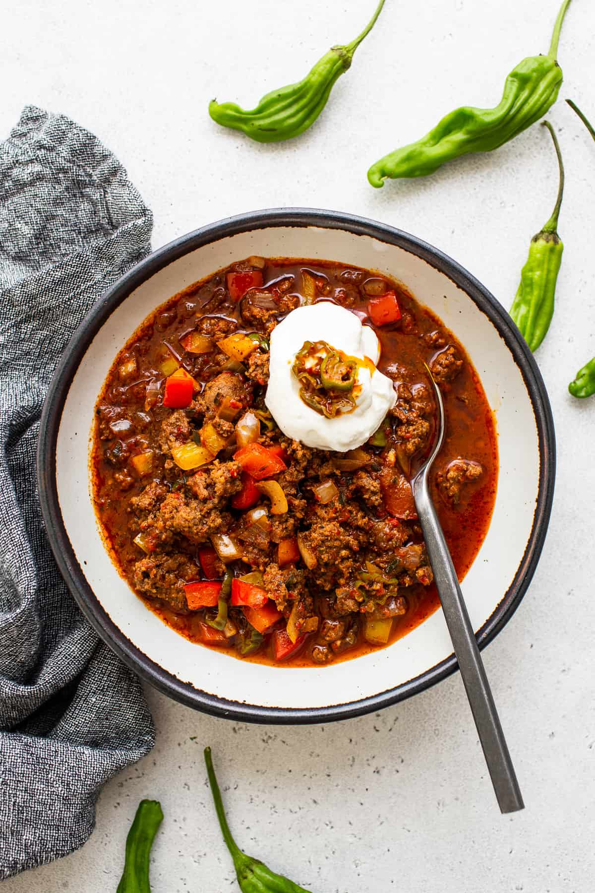 Texas chili in a bowl topped with sour cream and hatch chilis. 