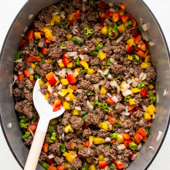 Peppers, onions, and ground beef in a pot.