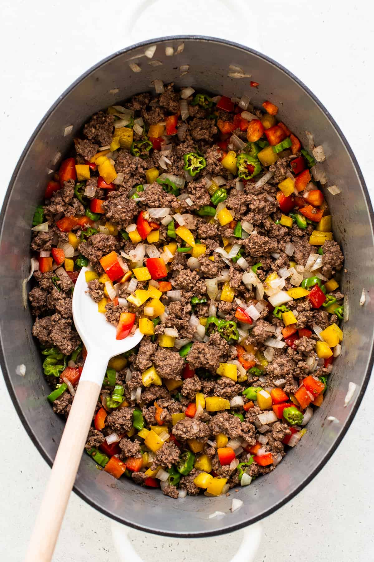 Ground beef, peppers, and onion cooking in a pot. 