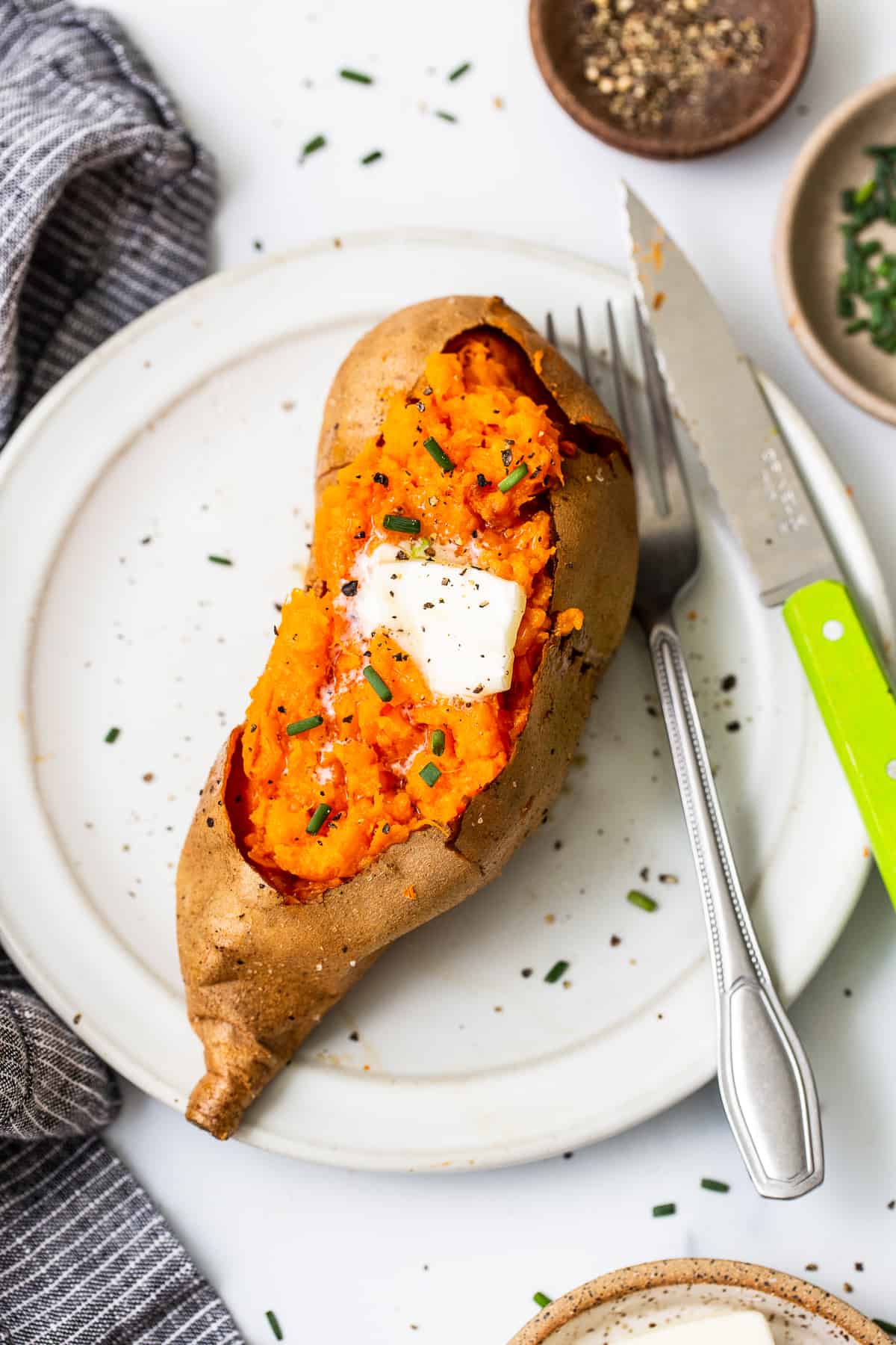 Baked sweet potato on a plate topped with butter.