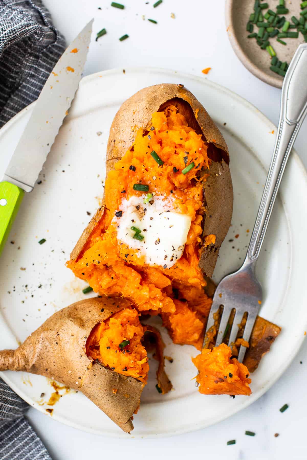 Baked sweet potato on a plate with a fork.