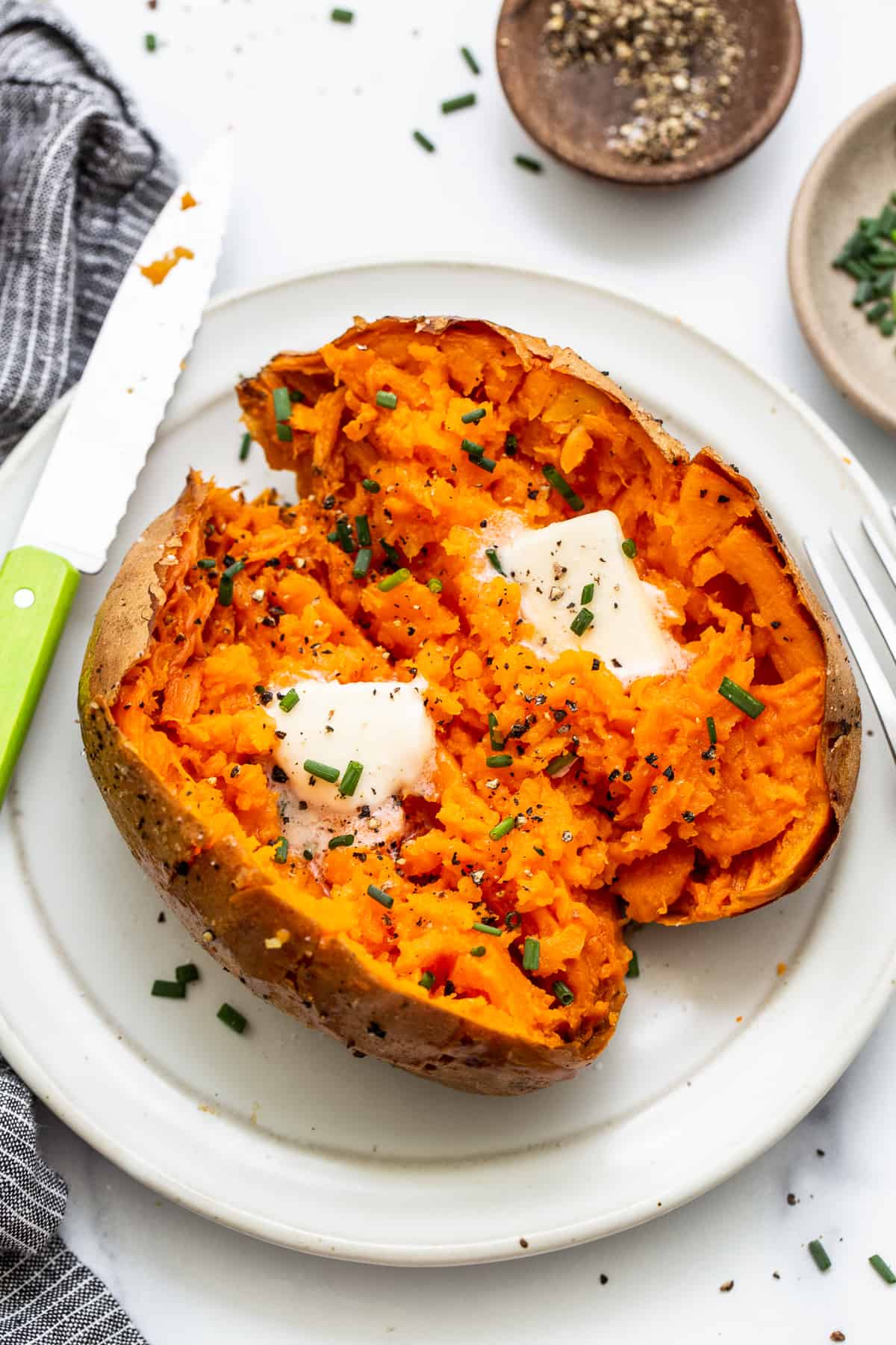 Baked sweet potato on a plate topped with butter.