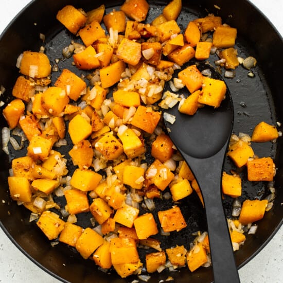 Squash in a skillet with a black spoon.