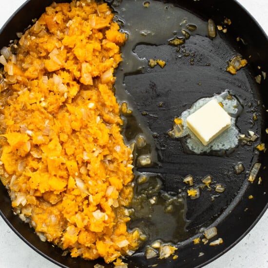 A frying pan with mashed sweet potatoes and butter.