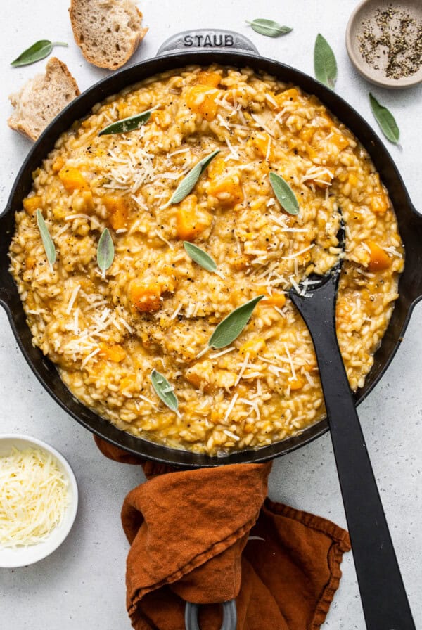 Pumpkin risotto in a skillet with parmesan cheese and sage.