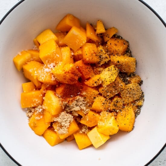A bowl filled with chopped squash and spices.
