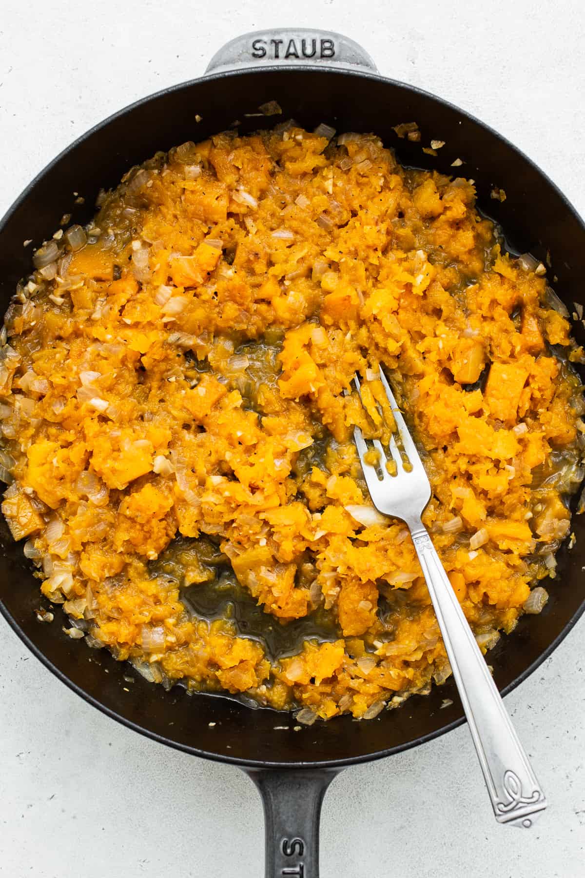 Smashing butternut squash with the back of a fork. 