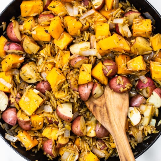 Butternut squash, red potatoes, and orzo in a skillet.