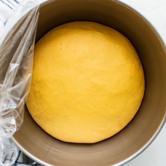 A yellow dough in a bowl with a towel on top.