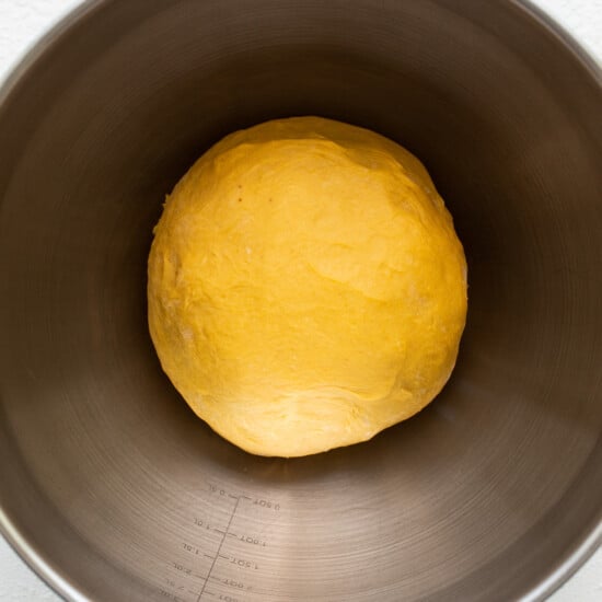 A ball of dough in a metal bowl.