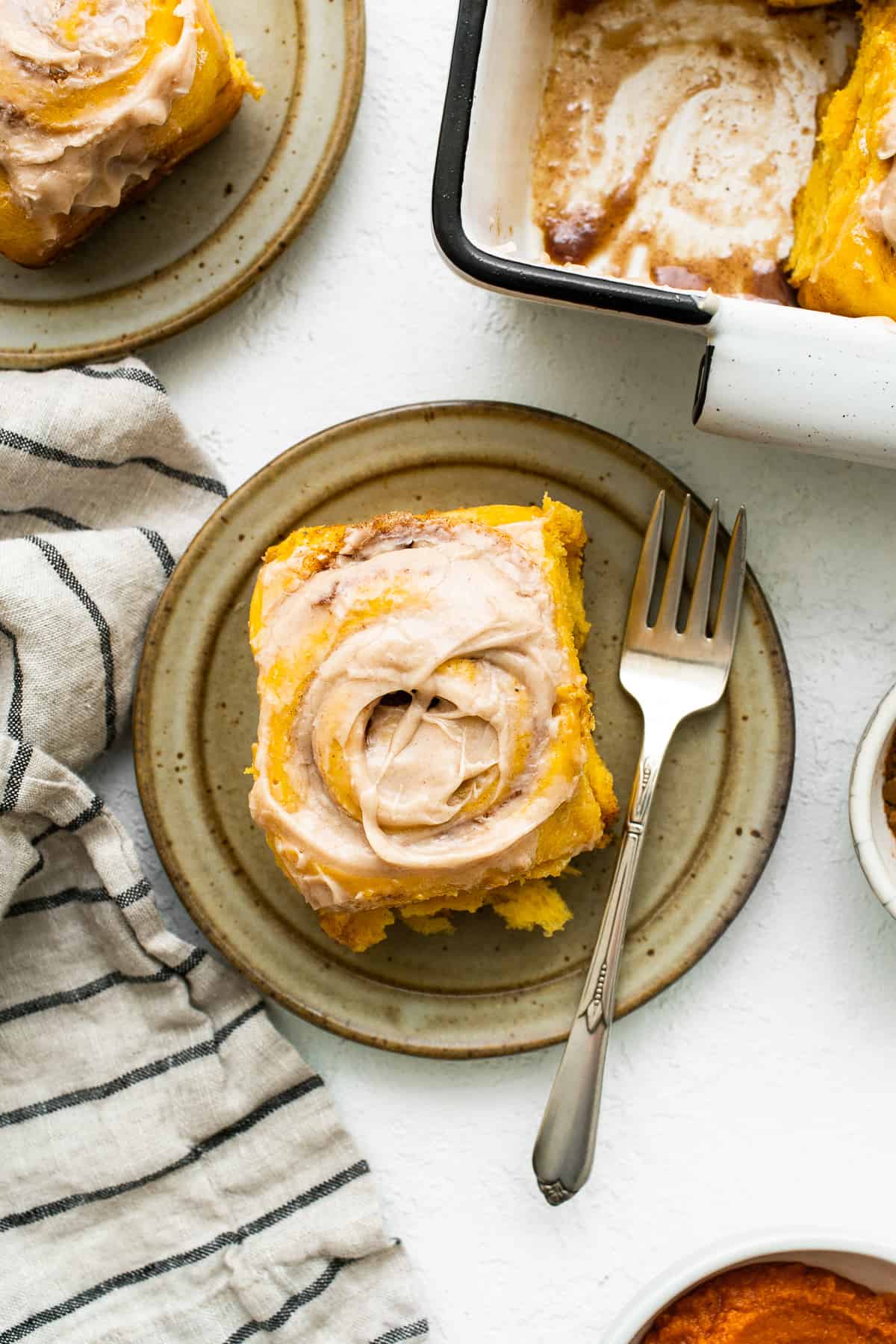 Pumpkin cinnamon roll on a plate with a fork.