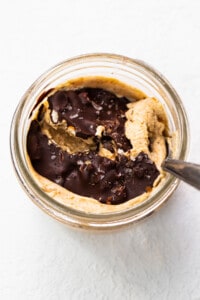 Peanut butter in a glass bowl with a spoon.