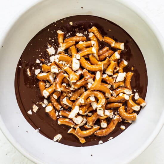 A white bowl filled with chocolate and pretzels.